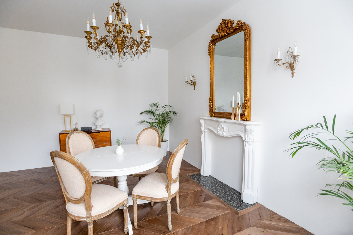 Decoração com espelhos na parede da sala: truques para manter o ambiente ainda mais bonito Sala com mesa de jantar e um espelho grande com moldura na parede. Imagem ilustrativa para texto decoração com espelhos na parede da sala.