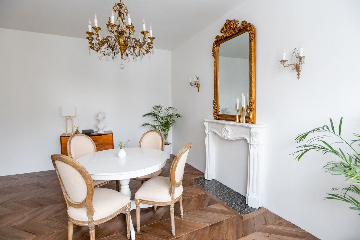 Sala com mesa de jantar e um espelho grande com moldura na parede. Imagem ilustrativa para texto decoração com espelhos na parede da sala.