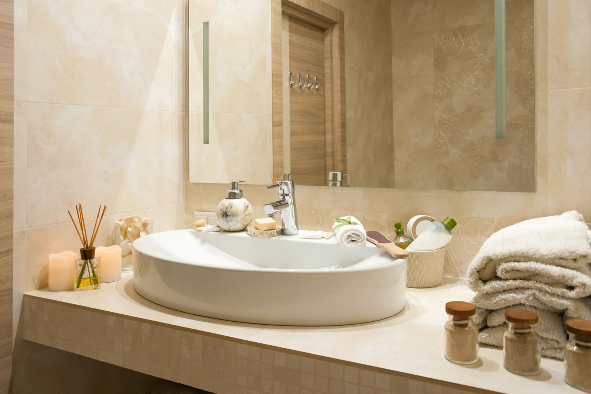 Banheiro com Porcelanato - Pia de banheiro com vários acessórios. Imagem ilustrativa para texto banheiro com porcelanato.