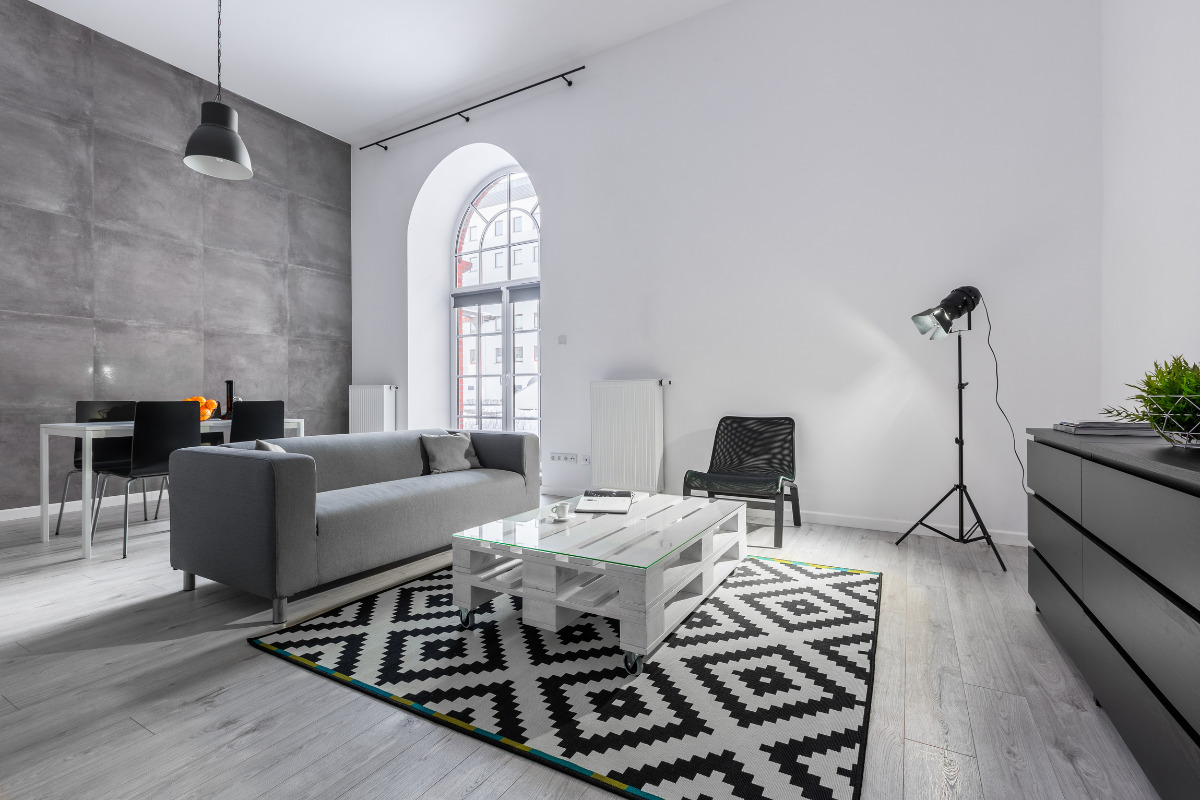 Como dividir ambientes de forma barata em 5 dicas simples! Como dividir ambientes de forma barata - Sala ampla com sofá dividindo as regiões. Imagem ilustrativa para texto como dividir ambientes de forma barata.