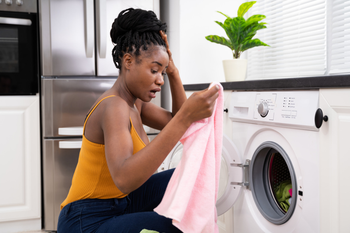 Mulher preocupada na hora de lavar roupa e tirar mancha. Imagem ilustrativa para texto como tirar mancha de gordura da roupa.