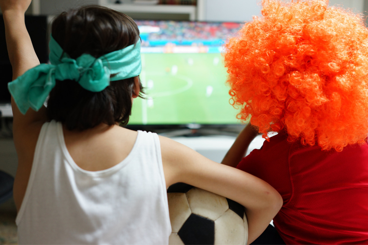 Dicas fáceis para fazer a decoração da Copa do Mundo no apartamento Crianças torcendo assistindo partida de futebol. Imagem ilustrativa para texto decoração copa do mundo.