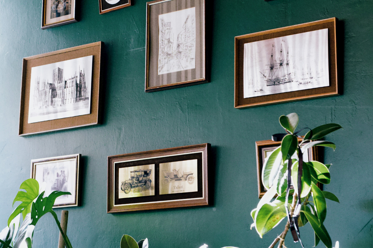 parede verde com vários quadros decorativos.