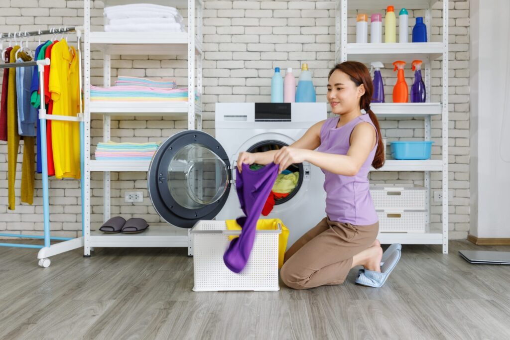 Decoração de lavanderia: dicas para planejar e organizar a sua decoração de lavanderia: mulher tirando roupas de máquina de lavar