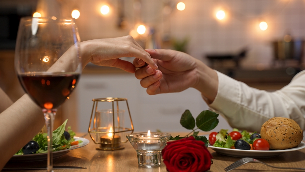 Amor em cada detalhe: dicas de decoração para o Dia dos Namorados Casal jantando em uma mesa posta para o Dia dos Namorados