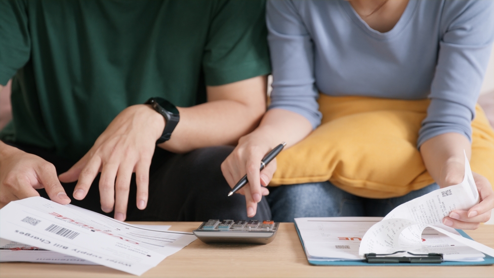 Composição de renda: transforme o sonho da casa própria em realidade Casal com uma calculadora fazendo contas juntos para entender a composição de renda